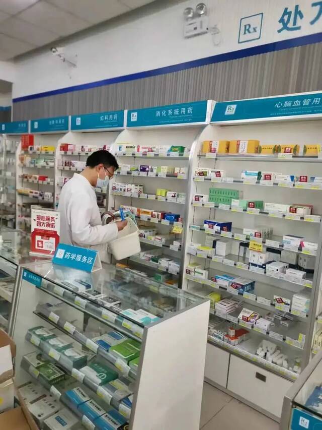 李中州在货架前根据订单拿药参考资料：新京报