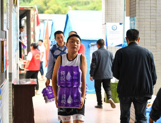 6月2日，在芦山县太平镇大河村安置点，小朋友帮忙运送矿泉水。新华社记者王曦摄