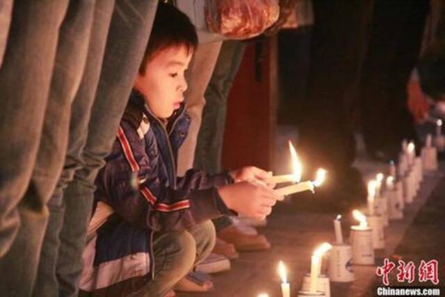 资料图：2013年04月20日08时02分，四川省雅安市芦山县发生7.0级地震。图为小男孩点燃蜡烛祈福。张一辰摄