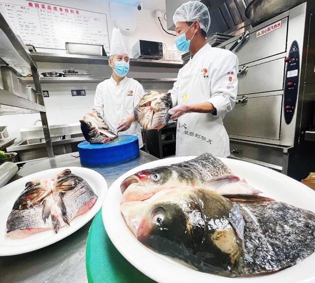 曲园酒楼厨师长、中国烹饪大师张景严（左一）对鱼头等食材进行查验。图/受访者供图
