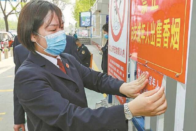 检察干警与市场监管人员一起张贴禁止向未成年人售酒的提示。