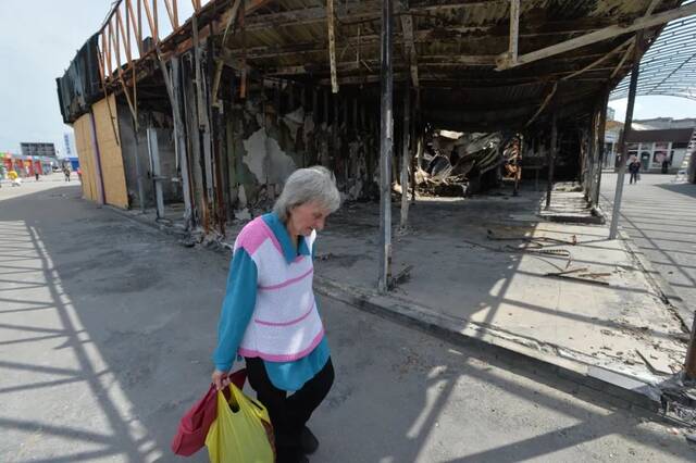 6月1日，在乌克兰哈尔科夫市东部北萨尔托夫卡，一名老人从被炸毁的商铺前经过。新华社发（彼得·德鲁克摄）