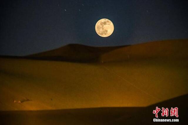 资料图：一轮超级圆月现身甘肃古郡敦煌夜空。图为在鸣沙山月牙泉景区观赏大漠圆月。（多重曝光）中新社发王斌银摄