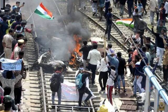 17日，印度年轻人在塞康德拉巴德市的铁轨上焚烧车辆，以抗议新征兵制度。（法新社）