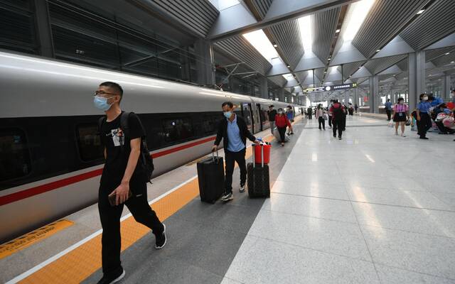 6月20日，北京丰台站正式开通运营，旅客们拎着行李准备上车。新京报记者王贵彬摄