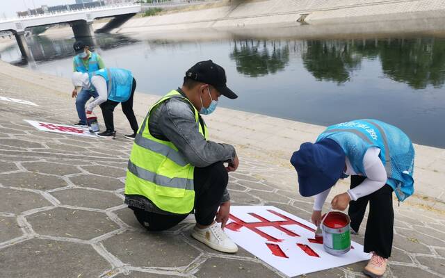 水务部门工作人员在河道护坡上涂刷警示语。北京市水务局供图