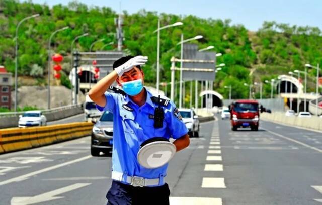 6月12日，乌鲁木齐市公安局交警支队快速路大队外环路中队民警在辖区指挥交通，身上的警服早已被汗水浸湿。来源：石榴云/新疆法制报