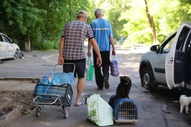 ↑6月18日，马里乌波尔当地居民在街头搬水。新华社发（维克托摄）