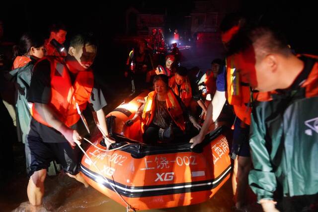 6月20日，德兴市泗洲镇，救援人员乘坐冲锋舟进入村庄转移被困人员。新华社记者周密摄
