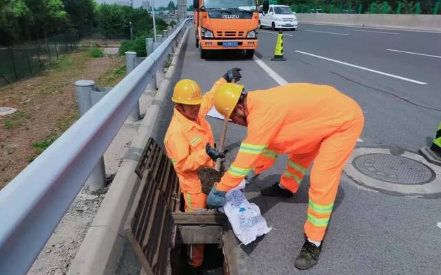 ▲工作人员提前清理高速公路上的排水沟，确保降雨时排水顺畅。首发养护供图