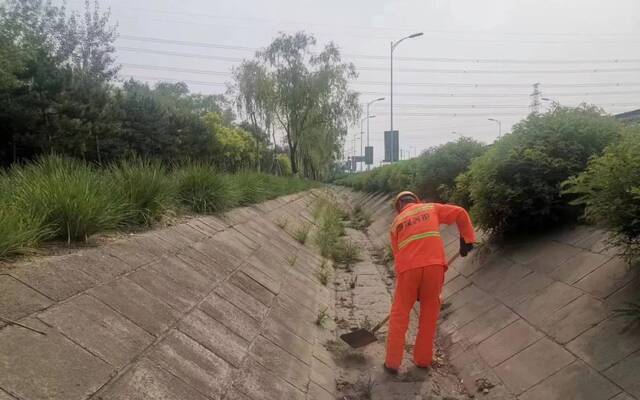 ▲工作人员提前清理高速公路上的排水沟，确保降雨时排水顺畅。首发养护供图