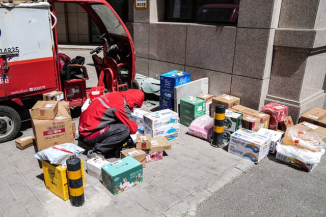 2022年4月26日，在北京市一小区门口，快递员在整理货品准备投递。新华社记者彭子洋摄