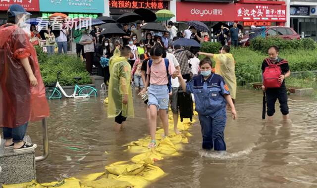 视频｜防汛沙袋铺出人行通道 地铁工作者雨中帮扶乘客