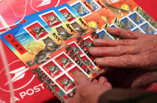 2022年1月22日，一名集邮爱好者在法国巴黎展示其购买的虎年生肖纪念邮票。（新华社记者高静摄）