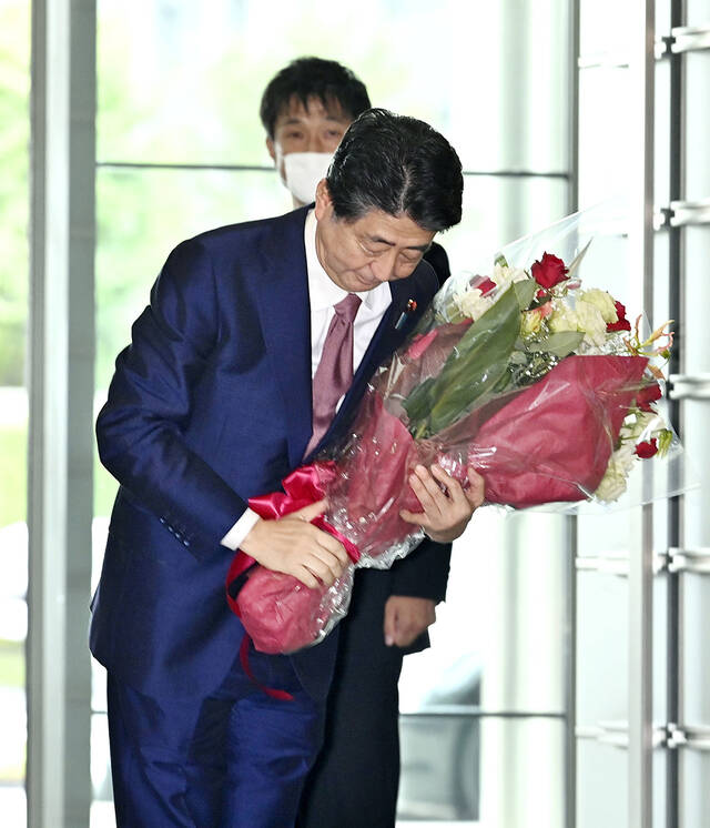 当地时间2020年9月16日，日本东京，即将卸任的日本首相安倍晋三最后一次在首相官邸举行内阁会议后，从工作人员那里收到鲜花。视觉中国资料图