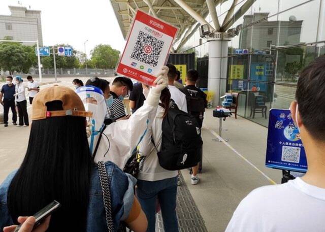 7月8日，西宁曹家堡国际机场候机大楼外，乘客们抵达后需要全部做核酸检测，有工作人员高举二维码收费牌。摄影/章轲