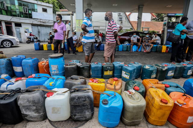 ↑4月2日，斯里兰卡科伦坡，人们拿着空罐在燃料泵站排队购买燃料。