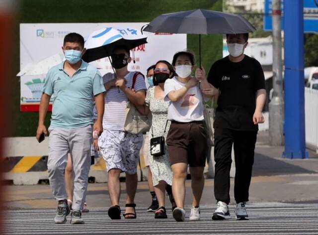 7月10日，在上海市闵行区，行人在烈日下行走。图片来源：新华社记者刘颖摄