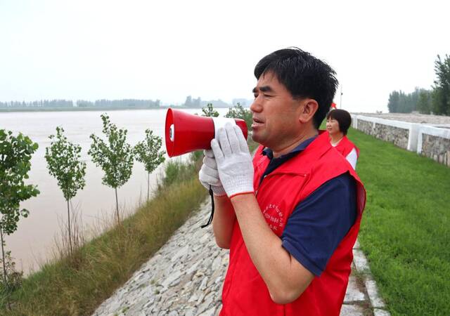 鄄城县阻泳志愿者林演华在黄河大堤上进行防溺水义务巡逻。新华社记者徐速绘摄