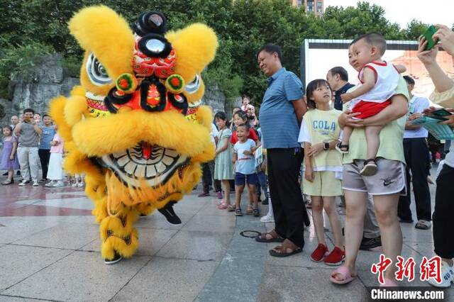 赖翊凡(狮头)与李洪江配合在县城诗乡广场练习舞狮吸引市民观看。瞿宏伦摄