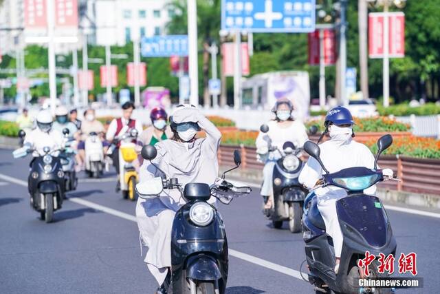 7月12日，广西南宁，市民“捂装”骑行。当日，南宁市气象台继续发布高温黄色预警信号。中新社记者陈冠言摄