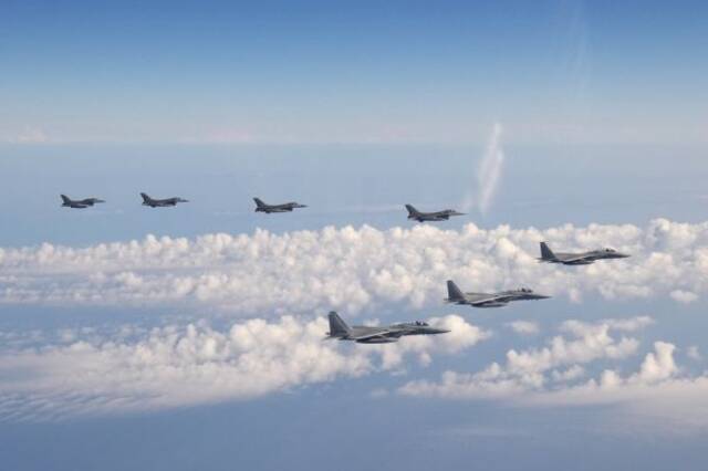 图说：日本自卫队的3架F-15战机、前线部队和4架F-16战机于2022年5月25日飞越日本海上空。（美联社）