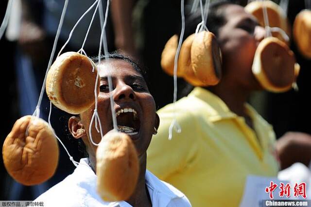 资料图：斯里兰卡民众在庆祝节日做游戏时，争相咬细绳吊起的面包。