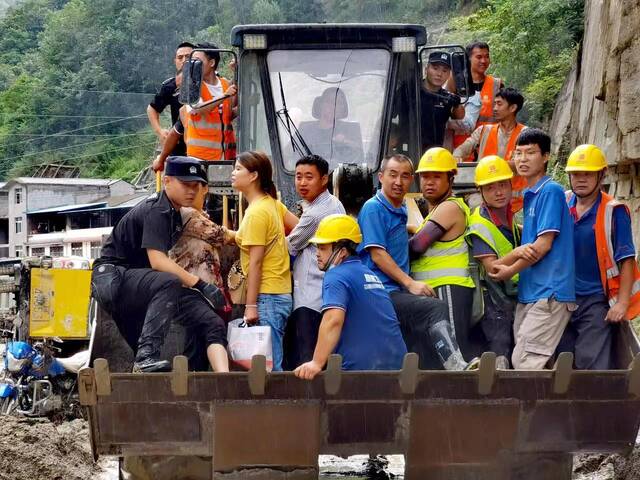 公安民警和消防等救援人员一起，乘坐推土机进入受灾严重的区域，成功将被困群众转移出来。