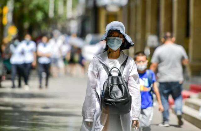 7月18日，新疆乌鲁木齐市，市民在闷热天气防晒出行。图/中新图片网