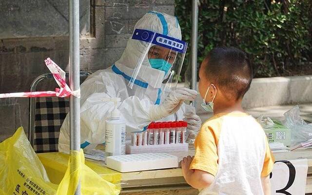 ▲资料图：核酸采集人员正在为一名小朋友采集咽拭子。新京报记者李木易摄