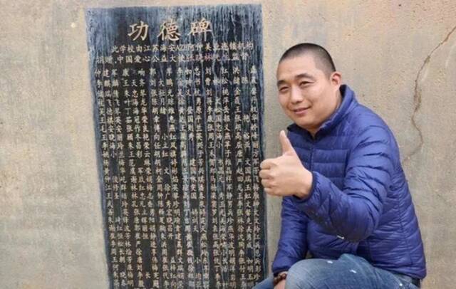 张晓林生前在昭觉县某爱心小学功德碑前留影。