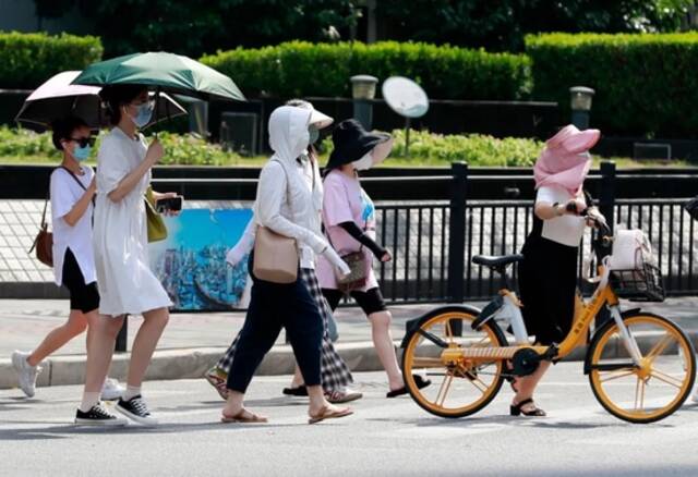  7月14日，上海街头的路人“各显神通”躲避炙热的阳光。图/中新图片网