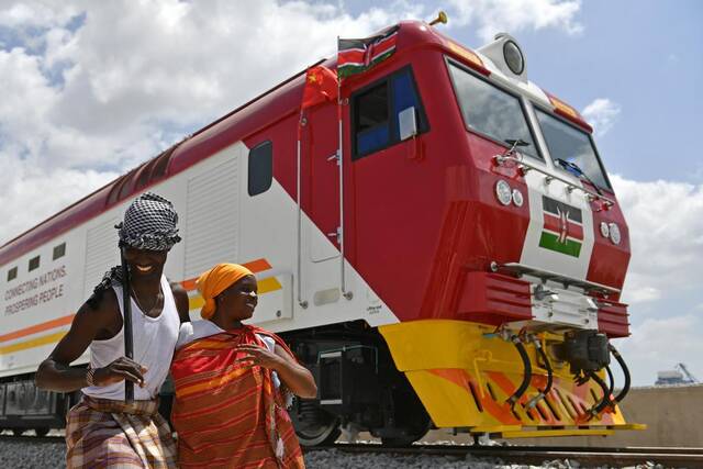 2017年1月11日，在肯尼亚蒙巴萨，当地民众在中国承制的蒙内铁路首批内燃机车旁载歌载舞。（新华社记者孙瑞博摄）