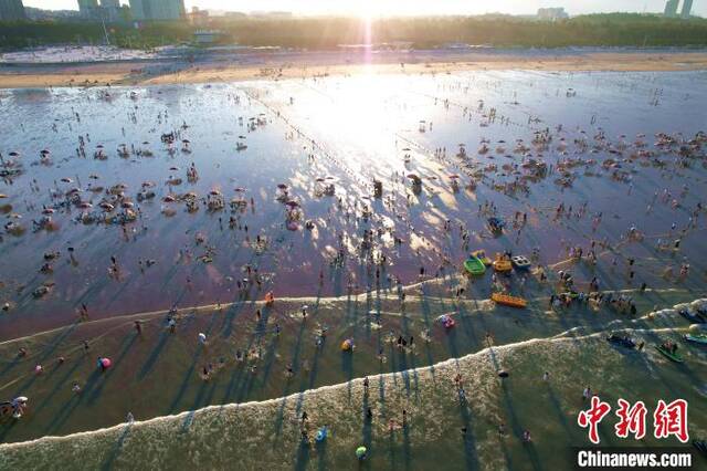 夏日炎炎，游客在海滩上游玩避暑。王东明摄