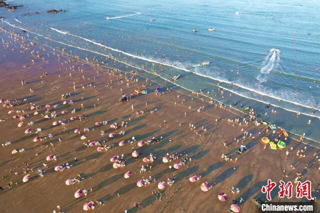 夏日炎炎，游客在海滩上游玩避暑。王东明摄