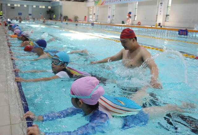 7月21日，在河北省固安县市民活动中心游泳馆，游泳教练指导小学员们练习蛙泳动作。新华社发（门丛硕摄）