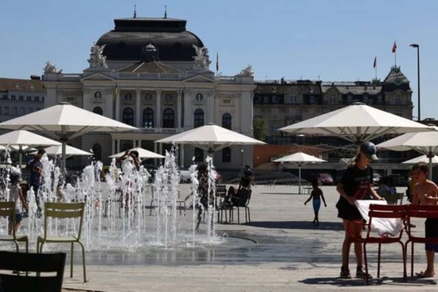 当地时间2022年7月19日，瑞士苏黎世，热浪笼罩着所有欧洲城市，这里是位于Bellevue广场和歌剧院之间的“Sechseläuten广场”，儿童和成人在寻找阴凉处乘凉或是在喷泉处解暑。图/IC photo