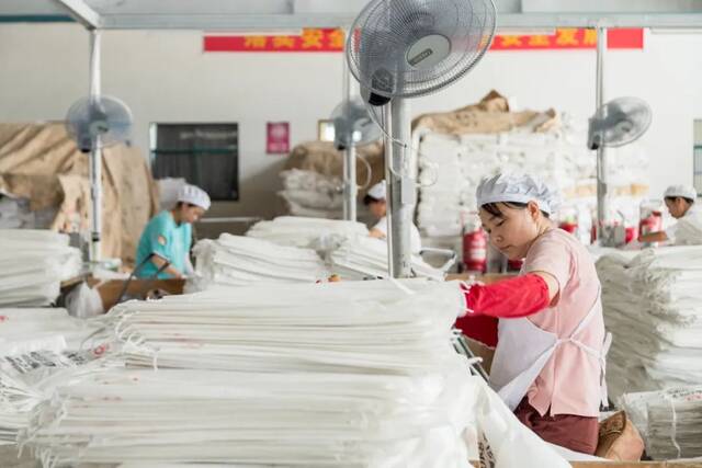 2021年7月22日，江苏省淮安市洪泽区西顺河镇工业园区某包装企业生产车间工人在赶制产品订单。（图|视觉中国）