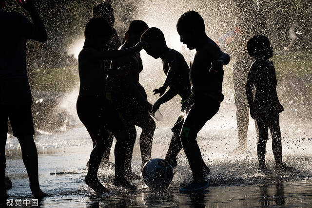 当地时间2022年8月8日，西班牙首都马德里持续高温，孩子们在喷泉里踢足球。视觉中国图