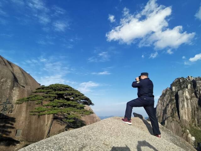 胡晓春手持望远镜，正在检查迎客松状况。王锐摄