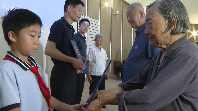 南京大屠杀幸存者夏淑琴向曾外孙李玉瀚颁发“南京大屠杀历史记忆传承人”证书。新华社记者刘宇轩摄