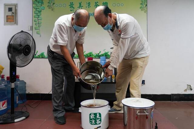 图为志愿者把烧好的凉茶倒入茶桶。新华社记者殷晓圣摄