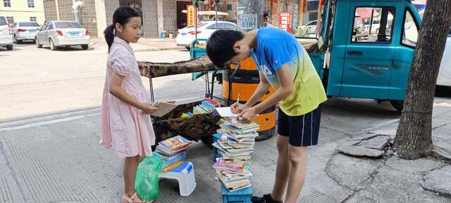 2022年暑假，镇上的小朋友来流动借阅车借阅书籍，王子悦（右一）正在登记。（受访者供图）