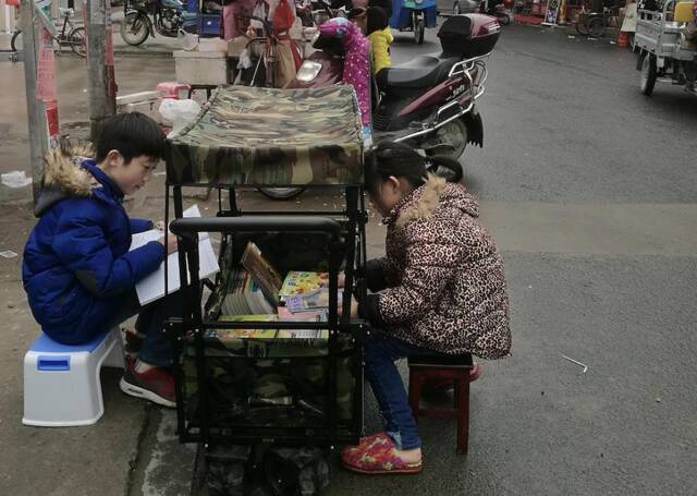 2019年寒假，王子悦（左一）推着流动借阅车去“赶集”。（受访者供图）