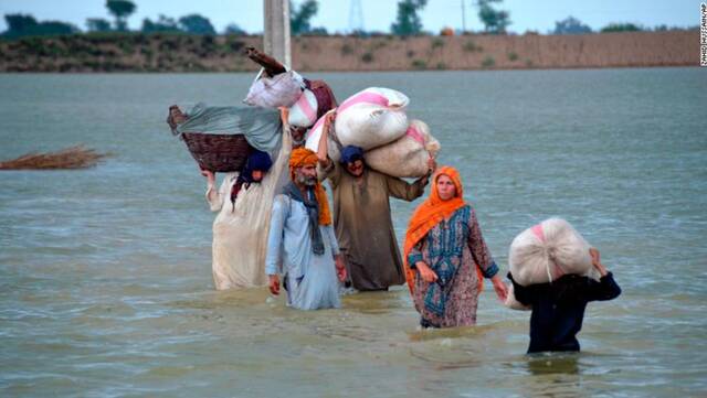 24日，俾路支省一个流离失所的家庭涉水穿过洪水区。图源：CNN