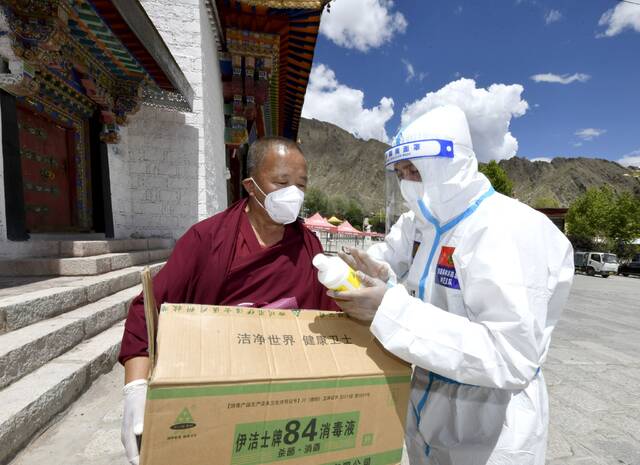8月14日，西藏拉萨，志愿者为哲蚌寺送来防疫物资，并向僧人讲解消毒液使用方法。李林摄/IC photo