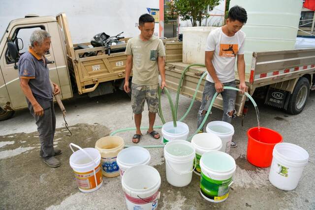 8月26日，在沿河县谯家镇谯家铺村，志愿者在给缺水的村民送水。新华社记者杨文斌摄