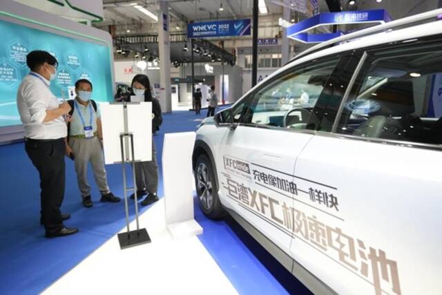 8月26日，2022世界新能源汽车大会上，工作人员向参观者介绍一款搭载可快速充电电池的新能源汽车。新华社记者鞠焕宗摄