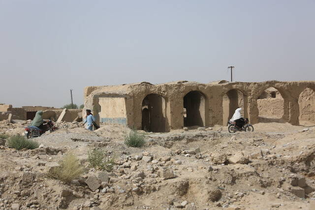 8月23日，在阿富汗南部赫尔曼德省桑金地区，人们走在废墟之中。新华社发（塞夫拉赫曼·萨菲摄）