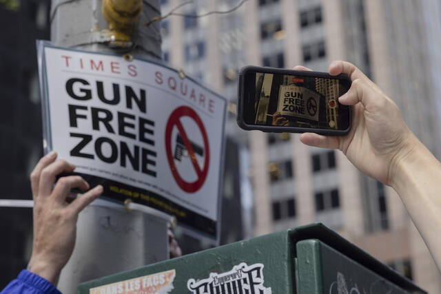 8月31日，在纽约时代广场附近，人们拍摄设立的“禁枪区”标识牌。